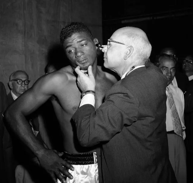 Heavyweight champion Floyd Patterson, and challenger, Tommy (Hurricane) Jackson, can hold no secrets from doctors examining them before their title bout later in the day at New York's Polo Grounds on July 29, 1957. At the examining room in winter garden theatre, a doctor checks Patterson's ear. Jackson, having his temperature checked, shushes a bystander. (Photo by Anthony Camerano/AP Photo)