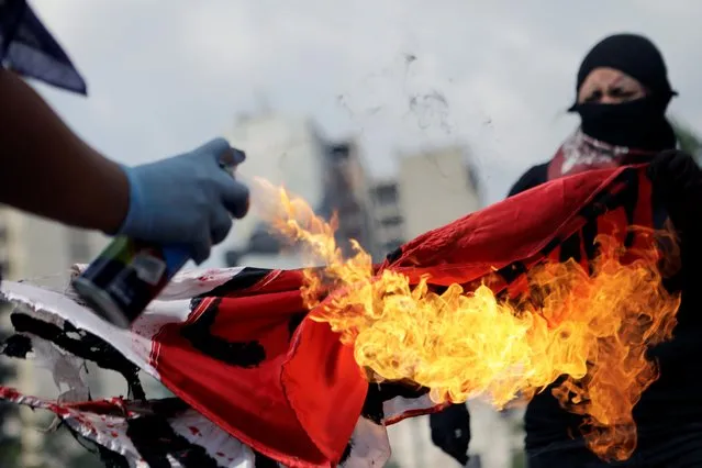 Women burn a flag as they take part in a march to demand justice for the victims of gender violence and femicides in Mexico City, Mexico on August 16, 2020. (Photo by Raquel Cunha/Reuters)