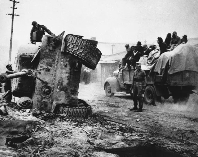 Men strip gear from a Pershing tank after overturning it to keep road clear during retreat of United Nations forces from North Korea on December 14, 1950. Tank's track had become dislodged. Later a demolition crew burned the machine. (Photo by AP Photo)