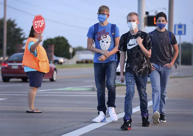 Freshmen Mason Mathis, left, Travis Ryan and Seth Wood make their way to school on the first day of in-person instruction at Owasso schools Thursday, Sept. 17, 2020 in Owasso, Okla. (Photo by Mike Simons/Tulsa World via AP Photo)