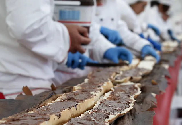 Bakers smear a record long baguette with Nutella at the Expo 2015 world's fair, in Rho, near Milan, Italy, Sunday, October 18, 2015. A judge from Guinness World Records has certified a 122-meter -long (400-foot-long) baguette baked at the Milan Expo 2015 World's Fair as the longest in the world. (Photo by Antonio Calanni/AP Photo)