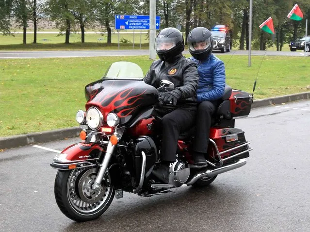 Belarusian President Alexander Lukashenko rides with his youngest son Nikolai as he arrives for the meeting with motorbikers in outskirts of Minsk, Belarus, Saturday, September 24, 2016. About three thousand bikers from Belarus, Russia and Europe have gathered in Minsk for the parade marking the closing of the 2016 season. (Photo by Gennady Zhinkov/BelTA Photo via AP Photo)