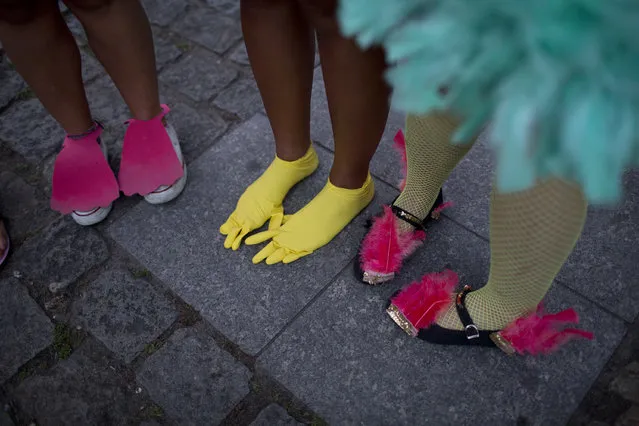 In this February 3, 2018 photo, a woman wears plastic, yellow gloves on her feet as part of her bird costume during the block party “Maria vem com as outras”, or “Maria, join the other women”, in Rio de Janeiro, Brazil. Many women in Latin America's largest nation are doing exactly that during this year's Carnival celebrations, with block parties of all-female musicians, popular accessories with messages like “my breasts, my rules” and several campaigns to report and crackdown on harassment. (Photo by Silvia Izquierdo/AP Photo)