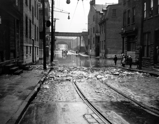 This is a view of Pittsburgh's low-lying north side section flooded with water as the Allegheny River reached its peak at 27.3 feet and started falling, leaving ice cakes in the streets on December 19, 1937. (Photo by AP Photo)