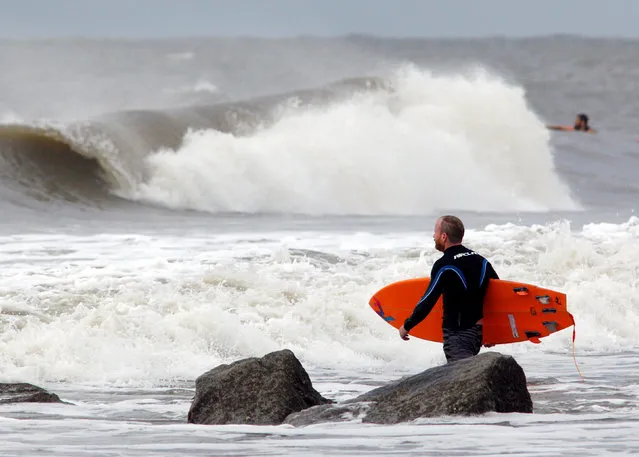 A surfer makes his way out into the waves as the winds and surf begin to intensify ahead of the arrival of Hurricane Matthew, in Folly Beach, South Carolina, U.S. October 6, 2016. (Photo by Jonathan Drake/Reuters)