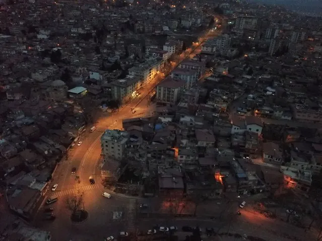 An aerial view taken on the evening of March 5, 2023 shows a lit main road and streets left in darkness in Kahramanmaras, one month after a massive earthquake struck south-east Turkey. A massive 7.8-magnitude earthquake rocked huge swathes of Turkey and parts of Syria on February 6, 2023, killing more than 50,000 people in both countries, with some 46 000 on the Turkish side. One month on, teams of workers are still toiling to clear the rubble that now dominates quake-hit cities, as the country faces faces the daunting task of rebuilding flattened cities, with tens of thousands buried and many survivors barely subsisting in tents or containers. Turkish officials said 214,000 buildings collapsed following the quake, many of them in Hatay and Kahramanmaras. (Photo by Eylul Yasar/AFP Photo)
