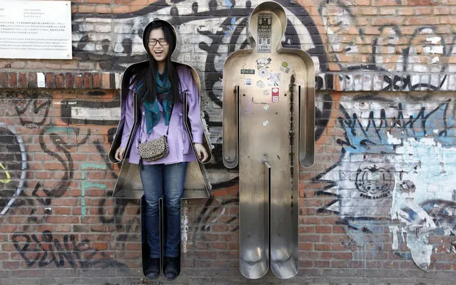 A visitor reacts as she poses for a photograph in an art installation entitled “You and Me” in Beijing's 798 art area April 18, 2013. (Photo by Jason Lee/Reuters)