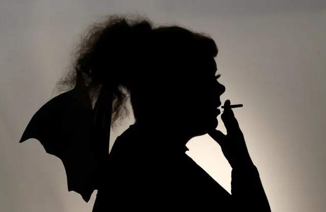 A woman wearing Halloween bat wings smokes in Durham, Britain on October 31, 2020. (Photo by Lee Smith/Reuters)