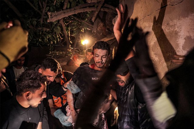 Palestinian civil defense workers and local residents help a wounded man evacuate a house in Rafah, Gaza, that was struck by Israel on Tuesday, May 7, 2024. Israel's attack in the city has expanded from airstrikes to ground operations, new satellite images obtained by CNN from Planet Labs show. The ground operations follow a series of airstrikes that destroyed several buildings over a 24-hour period and killed at least four people, according to a local hospital. (Photo by AFP Photo/Stringer)