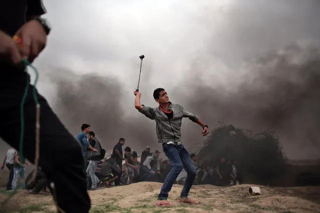 A Palestinian protester hurls stones using a sling shot during clashes with Israeli soldiers on the Israeli border with Gaza in Bureij, central Gaza Strip, Friday, November 6, 2015. (Photo by Khalil Hamra/AP Photo)