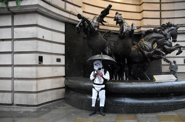 A man dressed as a 'stormtrooper' character from the Star Wars film franchise shields himself from the rain in Piccadilly Circus in London, Britain, March 29, 2018. (Photo by Toby Melville/Reuters)