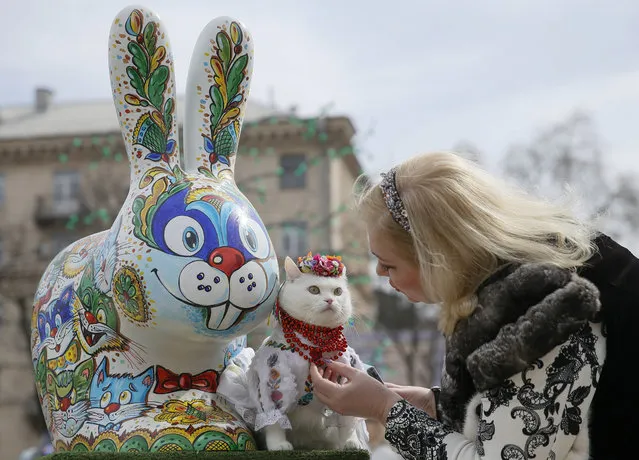 A woman dresses her cat before taking pictures near a painted Easter Bunny, displayed in a square as part of the upcoming Orthodox Easter celebration, in central Kiev, Ukraine April 5, 2018. (Photo by Valentyn Ogirenko/Reuters)