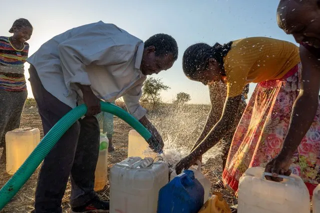 Tigrinyan refugees who fled Ethiopia's conflict, help each other fill their gallons with water, in Umm Rakouba refugee camp in Qadarif, eastern Sudan, Thursday, December 10, 2020. (Photo by Nariman El-Mofty/AP Photo)
