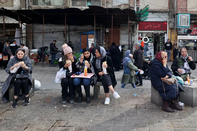 Women eat as they sit in a commercial area in Tehran on February 21, 2023. Iran's currency plunged to new lows on January 20 amid fresh European Union sanctions, crossing the psychologically important rate of 500,000 rials to a dollar in foreign exchange markets. (Photo by Atta Kenare/AFP Photo)