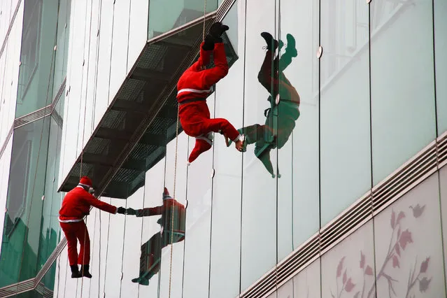 Members of the Slovenian Cave Rescue Association dressed as Santa Clauses rappel down the glass facade of a paediatric hospital in Ljubljana, Slovenia, December 21, 2020. (Photo by Borut Zivulovic/Reuters)
