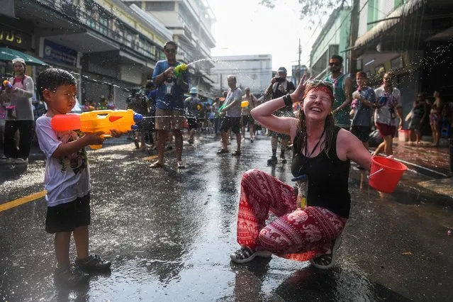 A boy and a tourist play with water as they celebrate during the Songkran holiday which marks the Thai New Year in Bangkok, Thailand on April 13, 2023. (Photo by Chalinee Thirasupa/Reuters)