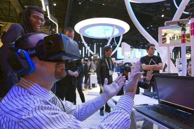 An attendee wearing an Oculus Rift virtual reality headset plays in a virtual volleyball game at the Intel booth during the 2015 International Consumer Electronics Show (CES) in Las Vegas, Nevada January 6, 2015. The goggles give a full 3D immersion and 360 degree view, a representative said. (Photo by Steve Marcus/Reuters)