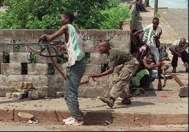 Liberian factional fighters loyal to Charles Taylor's National Patriotic Front of Liberia (NPFL) fire a high caliber machine gun at rival fighters loyal to Roosevelt Johnson, near the Barclay Training Center compound in downtown Monrovia Saturday, May 4, 1996. Despite the evacuation of Johnson from Monrovia to Accra, Ghana, Friday, heavy fighting continued in the Liberian capital city. (Photo by David Guttenfelder/AP Photo)