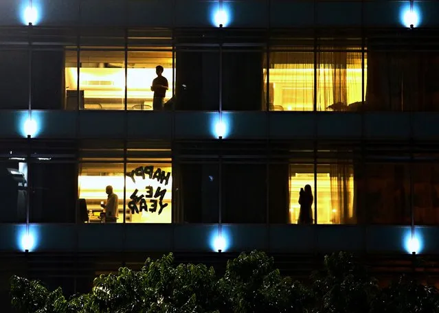 People stand at a hotel with a sign “Happy New Year” in one of its windows, during New Year's Eve in Jakarta, Indonesia, December 31, 2020. (Photo by Ajeng Dinar Ulfiana/Reuters)