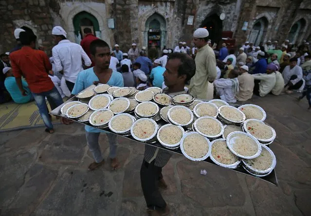 A man carries plates of rice to distribute among the Muslims for Iftar (breaking fast) meal during the holy month of Ramadan at the ruins of the Feroz Shah Kotla mosque in New Delhi, India, May 31, 2018. (Photo by Amit Dave/Reuters)