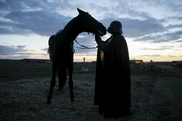 Darth Mykolaiovych Vader, who is dressed as the Star Wars character Darth Vader, poses for a picture as he caresses his horse at a stabling outside of Odessa, Ukraine, December 2, 2015. (Photo by Valentyn Ogirenko/Reuters)