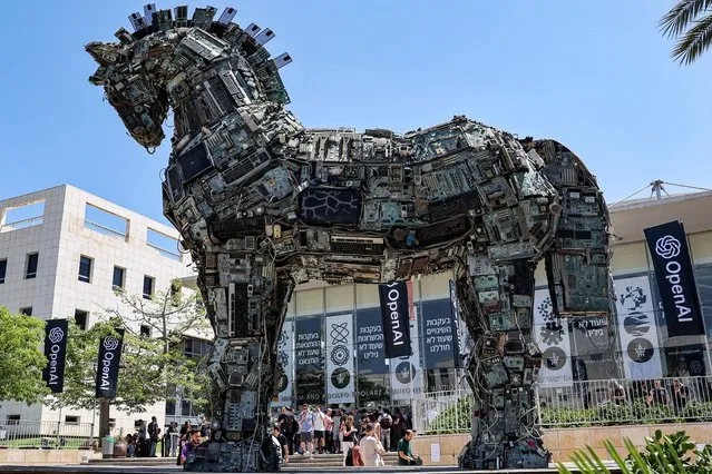 Banners of US artificial intelligence company OpenAI fly near an installation depicting the legendary “Trojan horse” built entirely out of microelectronic circuit boards and other computer components, outside at the campus of Tel Aviv University in Tel Aviv on June 5, 2023. (Photo by Jack Guez/AFP Photo)