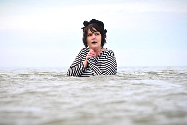 A participants wearing a 1900 style costume, takes part in the traditional last swim of the year, off the beach at Cabourg, northern France, on December 31, 2024. (Photo by Lou Benoist/AFP Photo)