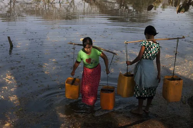 Girls wait to fetch water at a lake in Dala township, Friday, January 30, 2015, in the outskirts of Yangon, Myanmar. (Photo by Khin Maung Win/AP Photo)