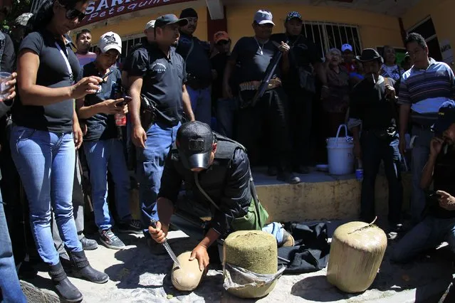 A member of the Community Police of the FUSDEG (United Front for the Security and Development of the State of Guerrero) slices open a bag of marijuana, which they said weighed approximately 40kg, after it was seized in a bus during an operation in the village of Petaquillas, on the outskirts of Chilpancingo, in the Mexican state of Guerrero, February 1, 2015. (Photo by Jorge Dan Lopez/Reuters)