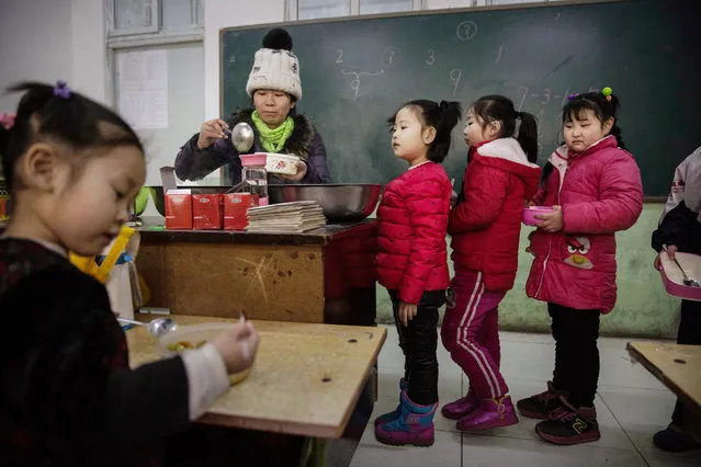 Chinese students who are children of migrants wait in line for lunch in a classroom at an un-official school on December 18, 2015 in Beijing, China. Schools for children of migrants are often unofficial or unrecognized by the state, and were established as a response to the education void created by the decades-long household registration or hukou system. A person's hukou entitles them to social services in their birthplace, meaning millions of Chinese who have migrated from rural areas to cities have been denied rights to urban public services. (Photo by Kevin Frayer/Getty Images)