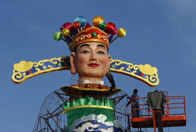 Labourers work on an 18m (59 feet) tall God of Fortune display ahead of the Lunar New Year celebrations along Marina Bay in Singapore February 6, 2015. The Chinese Lunar New Year on February 19 will welcome the Year of the Sheep (also known as the Year of the Goat or Ram). (Photo by Edgar Su/Reuters)