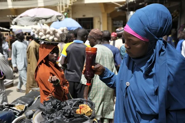 A woman sells locally made food at a market in Kano, Nigeria, Thursday, July 13, 2023. Nigeria's President Bola Tinubu has announced his government's plan to pay $10 monthly to poor households to ease the growing hardship caused by the scrapping of subsidies that had reduced the cost of gasoline. (Photo by Sunday Alamba/AP Photo)