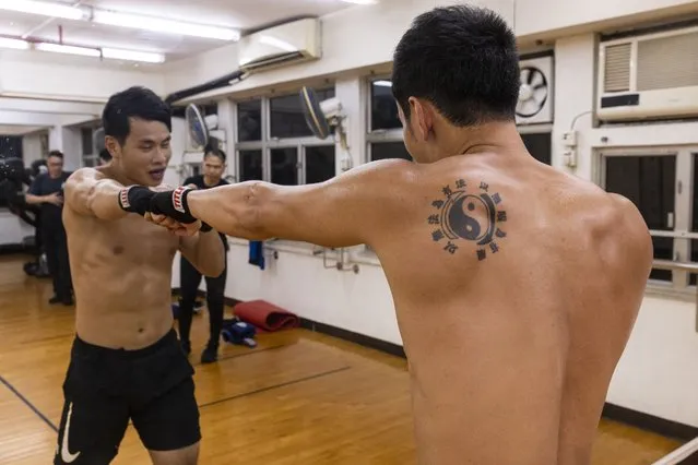 Adrian Li trains as he wears a tattoo representing the Jeet Kune Do Emblem which traditional Chinese characters read: “Using no way as way” and “Having no limitation as limitation” during a Jeet Kune Do class in Hong Kong, Wednesday, July 19, 2023. (Photo by Louise Delmotte/AP Photo)