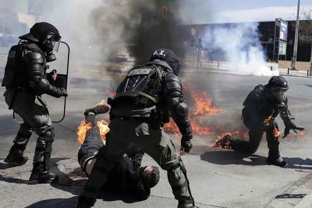 A protester, bottom, and riot policeman react after catching fire from a gasoline bomb during a protest in the the northern city of Thessaloniki, Greece, Thursday, April 15, 2021. The protester was arrested on suspicion of throwing a gasoline bomb, authorities said. He was taken to hospital after being injured during his arrest, apparently when a gasoline bomb landed nearby, catching both the protester and the riot policeman detaining him. Clashes between small groups of demonstrators and police broke out in the northern Greek city of Thessaloniki at the end of a march to protest a new law allowing the policing of university campuses. (Photo by Achilleas Chiras/AP Photo)