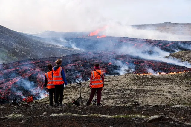 University of Iceland's observers stand in front of smoke billowing from flowing lava during an volcanic eruption near Litli Hrutur, south-west of Reykjavik in Iceland on July 10, 2023. A volcanic eruption started on July 10, 2023 around 30 kilometres (19 miles) from Iceland's capital Reykjavik, the country's meteorological office said, marking the third time in two years that lava has gushed out in the area. “The eruption is taking place in a small depression just north of Litli Hrutur, from which smoke is escaping in a north-westerly direction”, the office said. Footage circulating in the local media shows a massive cloud of smoke rising from the ground as well as a substantial flow of lava. (Photo by Kristinn Magnusson/AFP Photo)