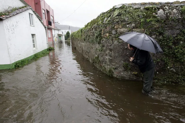 A man walks through the flooded streets at Neda in Galicia, Spain, on 08 January 2016. The heavy rains have oferflowed various rivers in Galicia causing floods in various parts of the region. (Photo by Kiko Delgado/EPA)