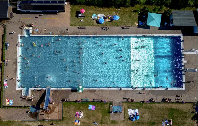 People spend time in a public pool in Wehrheim near Frankfurt, Germany, on a hot Saturday, July 8, 2023. (Photo by Michael Probst/AP Photo)