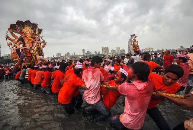 Devotees pull an idol of elephant-headed Hindu God Ganesha for immersion in the Arabian Sea in Mumbai, India, on September 18, 2013. The immersion marks the end of the ten-day long Ganesh Chaturthi festival that celebrates the birth of the Hindu God. (Photo by Rafiq Maqbool/Associated Press)