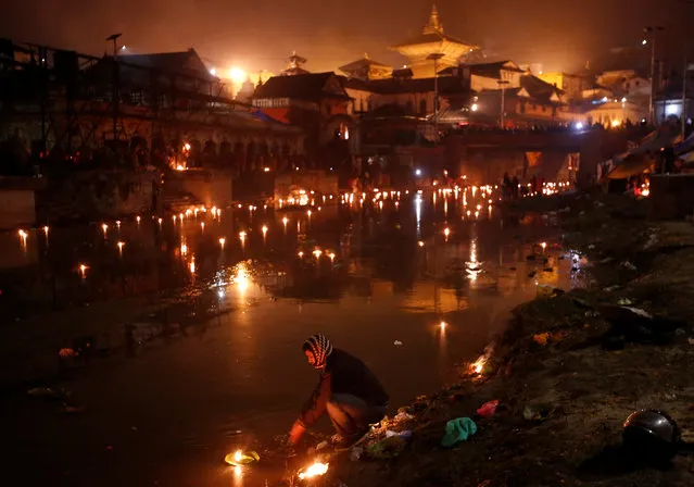 A devotee (C) performs religious ritual on the bank of Bagmati River flowing through the premises of Pashupatinath Temple, during the Bala Chaturdashi festival, in Kathmandu, Nepal November 28, 2016. (Photo by Navesh Chitrakar/Reuters)