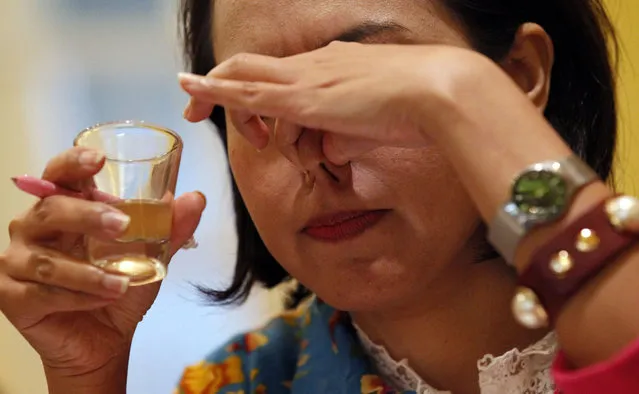 In this Thursday, February 19, 2015 photo,  a participant holds her nose as she tries a “Cricket Consomme”, a broth made from crickets at a seminar on edible insects at Le Cordon Bleu. (Photo by Sakchai Lalit/AP Photo)