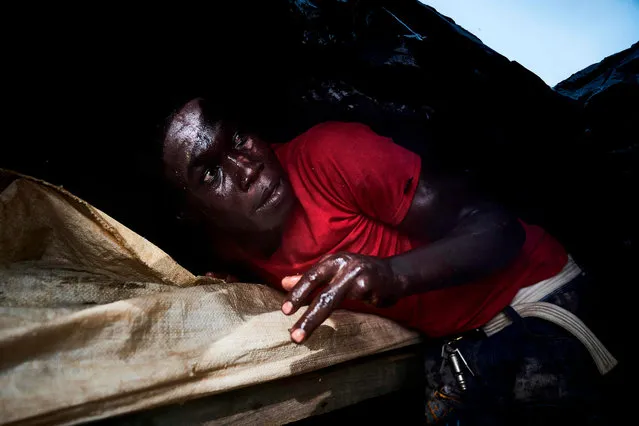 A Malian sand digger takes shelter under a plastic tarpaulin during a storm over the Niger River, near Kangaba in Mali' s southwestern Koulikoro region, on October 1, 2018. (Photo by Michele Cattani/AFP Photo)