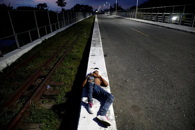 A Central American migrant, part of a caravan trying to reach the U.S., waits on the bridge that connects Mexico and Guatemala as he waits to regroup with more migrants, in Tecun Uman, Mexico October 26, 2018. (Photo by Edgard Garrido/Reuters)