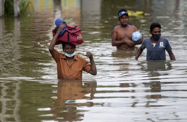 Sri Lankans wade through an inundated street following heavy rainfall at Malwana, on the outskirts of Colombo, Sri Lanka, Saturday, June 5, 2021. Flash floods and mudslides triggered by heavy rains in Sri Lanka have killed at least four people and left seven missing, while more than 5,000 are displaced, officials said Saturday. Rains have been pounding six districts of the Indian Ocean island nation since Thursday night, and many houses, paddy fields and roads have been inundated, blocking traffic. (Photo by Eranga Jayawardena/AP Photo)