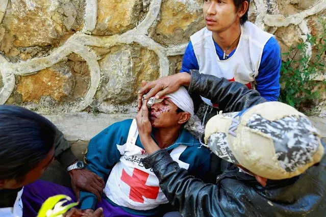 A volunteer with the Myanmar Red Cross Society, is helped after being wounded when the convoy he was in, was fired upon by the Myanmar National Democratic Alliance Army (MNDAA), according to the Myanmar army, between the capital of Kokang, Laukkai, and Chinshwehaw, February 17, 2015. (Photo by Soe Zeya Tun/Reuters)