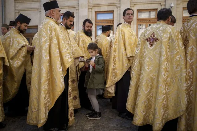 A girl stands among priests before the Saint Dimitrie Bassarabov, patron saint of the Romanian capital procession, in Bucharest, Romania, Tuesday, October 24, 2023. (Photo by Vadim Ghirda/AP Photo)