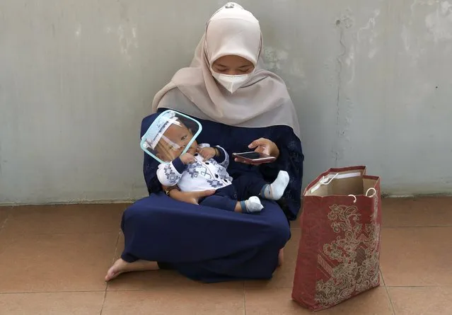 A woman wearing a face mask to curb the spread of coronavirus with her baby attends during an Eid al-Adha prayer at Zona Madina mosque in Bogor, Indonesia,Tuesday, July 20, 2021. (Photo by Tatan Syuflana/AP Photo)