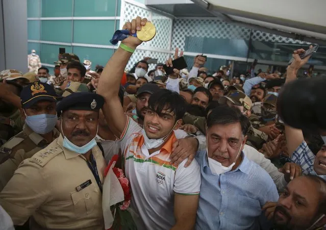 Olympic medallist Neeraj Chopra displays the gold medal he won in the men’s javelin at the Tokyo Games as he arrives for a rousing reception at the Indira Gandhi International Airport in New Delhi, India, Monday, August 9, 2021. (Photo by AP Photo/Stringer)