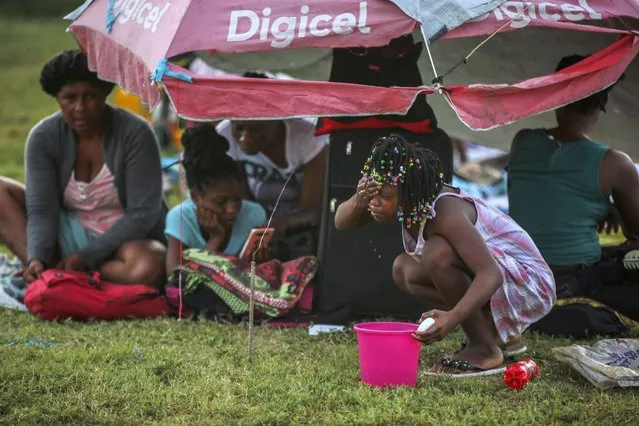 A girl washes her face after spending the night at a soccer field following Saturday´s 7.2 magnitude earthquake in Les Cayes, Haiti, Sunday, August 15, 2021. (Photo by Joseph Odelyn/AP Photo)