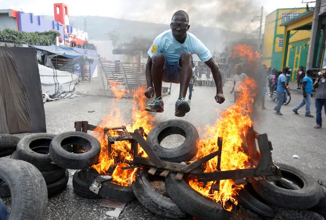 A protester jumps over a burning barricade during a protest against the government in the streets of Port-au-Prince, Haiti, February 10, 2019. (Photo by Jeanty Junior Augustin/Reuters)