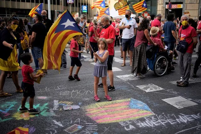 A girl waves a pro-independence flag as demonstrators march during the Catalan National Day in Barcelona, Spain, Saturday, September 11, 2021. Thousands of Catalans have rallied for independence from the rest of Spain in their first major mass gathering since the start of the pandemic. The march in Barcelona on Saturday comes before a meeting between regional leaders in northeast Catalonia and the Spanish government. (Photo by Joan Mateu Parra/AP Photo)